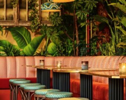 Tropical-themed seating with colorful stools and hanging lamps in a cozy setting. Maison Mermont.