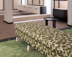 Green leaf-patterned upholstered bench on a green carpet in modern interior. Maison Mermont.