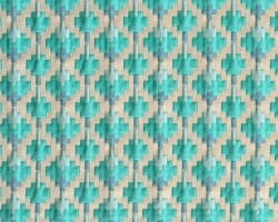 Teal geometric patterned fabric with symmetrical designs on a beige background, perfect for stylish home decor. Maison Mermont.
