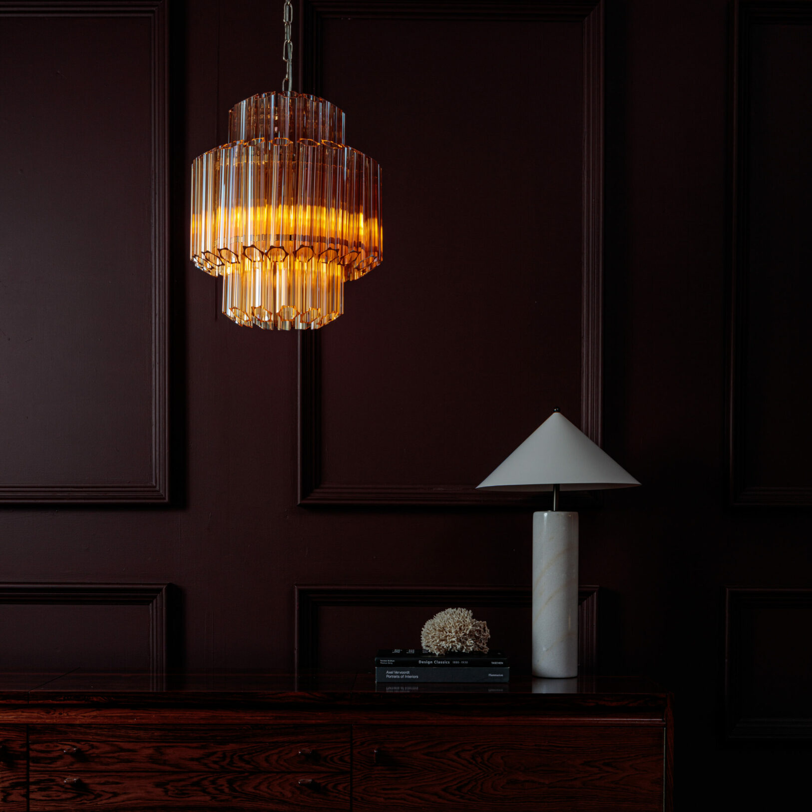 Amber-Small-Celesta-Chandelier Elegant crystal pendant light illuminating a dark wood room setting. Maison Mermont.