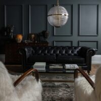 Large Clear Parisian Globe Pendant Elegant black leather chesterfield sofa paired with a modern glass coffee table in a stylishly decorated room. Maison Mermont.