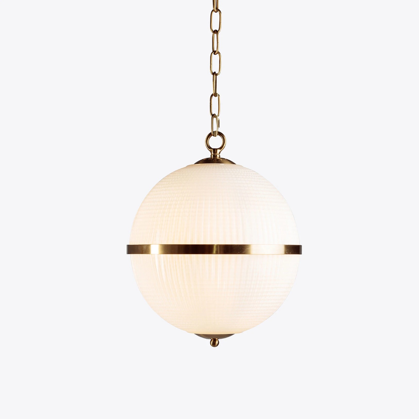 Elegant globe pendant light with a textured glass shade and brass accents, perfect for modern interiors. Maison Mermont.