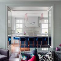 Stylish contemporary kitchen with blue velvet barstools and marble countertops. Maison Mermont.