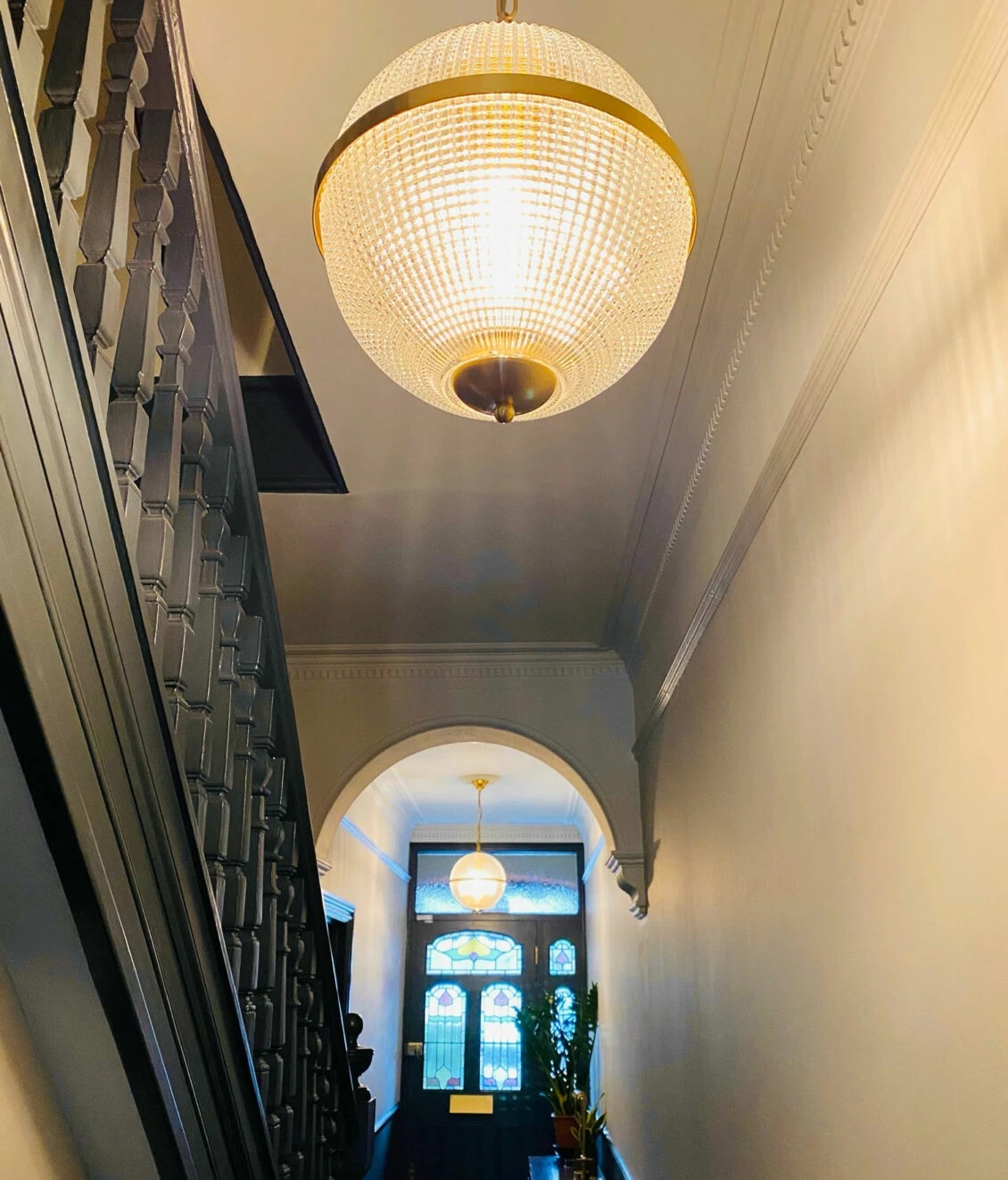 Small Clear Parisian Globe Pendant - Hallway Elegant pendant light illuminating a stylish hallway with a vintage staircase and stained glass door. Maison Mermont.