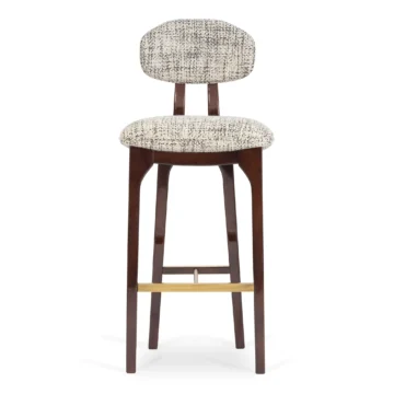 Elegant upholstered bar stool with a curved backrest and wooden legs, perfect for modern interiors. Maison Mermont.