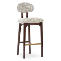 maison-mermont-silhouette-bar-stool-mix-02-translucent-dark-brown-oxidized-brushed-brass-02-insidherland Elegant upholstered bar stool with a curved backrest and wooden legs, perfect for modern interiors. Maison Mermont.