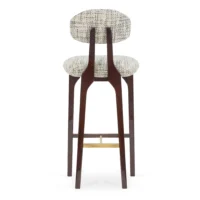 maison-mermont-silhouette-bar-stool-mix-02-translucent-dark-brown-oxidized-brushed-brass-05-insidherland Elegant upholstered bar stool with a curved backrest and wooden legs, perfect for modern interiors. Maison Mermont.