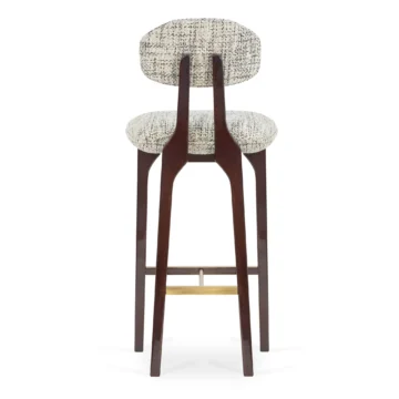 Elegant upholstered bar stool with a curved backrest and wooden legs, perfect for modern interiors. Maison Mermont.