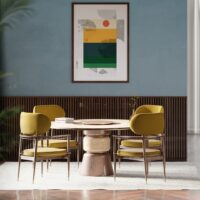 Modern dining room featuring a round wooden table and stylish yellow chairs against a blue backdrop. Maison Mermont.