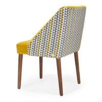 Stylish dining chair with geometric patterned back and yellow upholstery, featuring wooden legs. Maison Mermont.