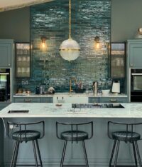 Stylish kitchen with blue tile backsplash, modern lighting, and marble countertop. Ideal for contemporary home design. Maison Mermont.
