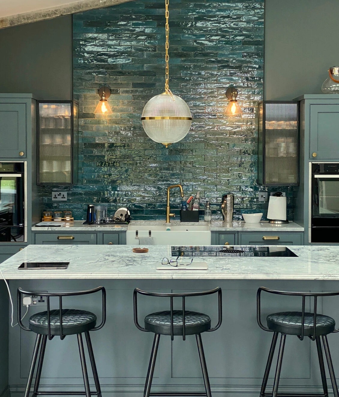 Stylish kitchen with blue tile backsplash, modern lighting, and marble countertop. Ideal for contemporary home design. Maison Mermont.